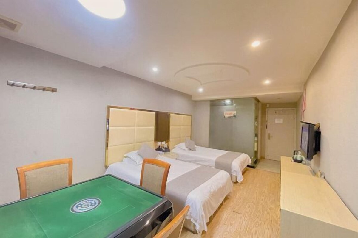 A hotel room with a pool table, two beds, a TV, and a desk.