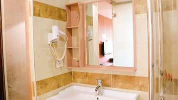 Een badkamer met een wastafel, een spiegel en een haardroger.