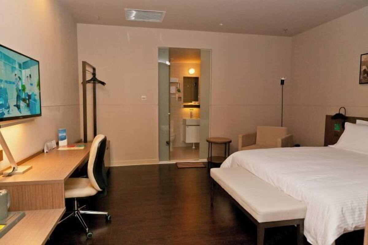 Une chambre d’hôtel avec un lit, un bureau, une chaise et une petite table.
