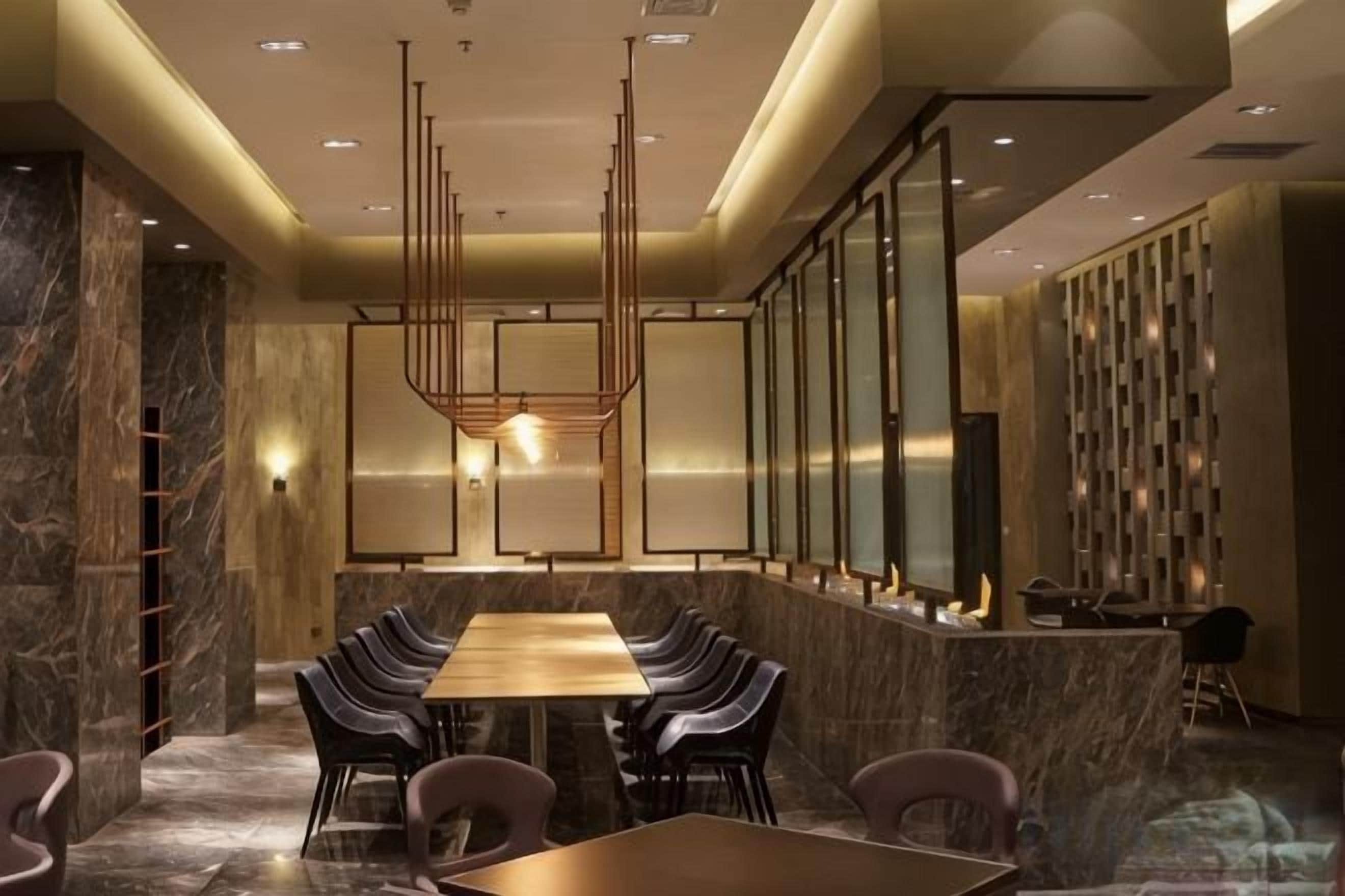 A modern conference room with a long table and chairs, a chandelier, and a reception desk.