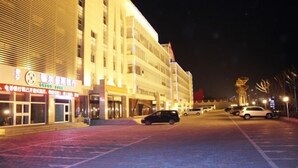 Ett hotell med flera våningar, en stor entré och en parkeringsplats.