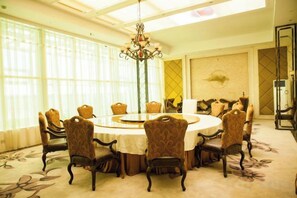Uma sala de jantar com uma mesa redonda, cadeiras e um lustre.