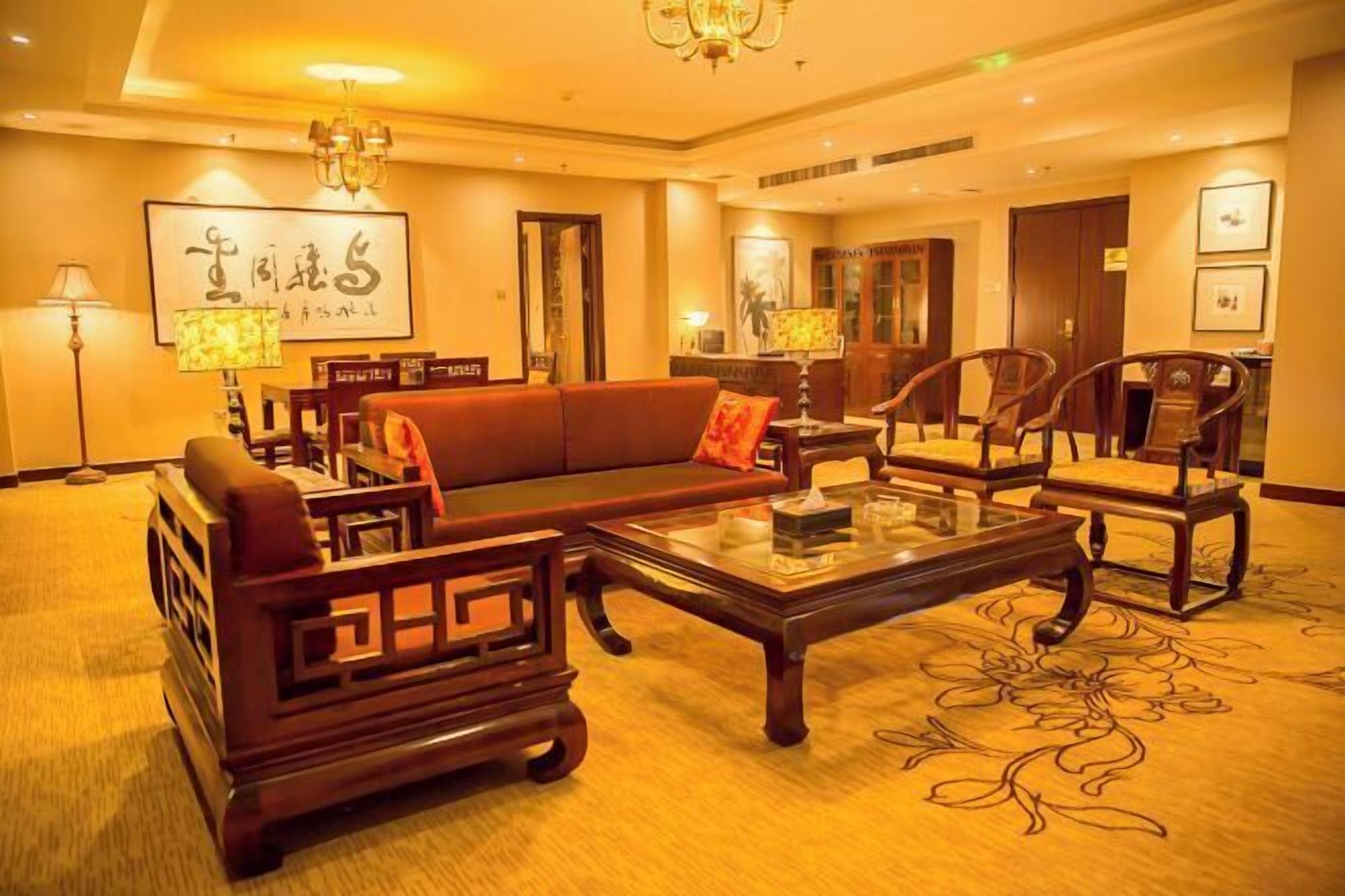 A hotel lobby with a sofa, chairs, a coffee table, and a chandelier.