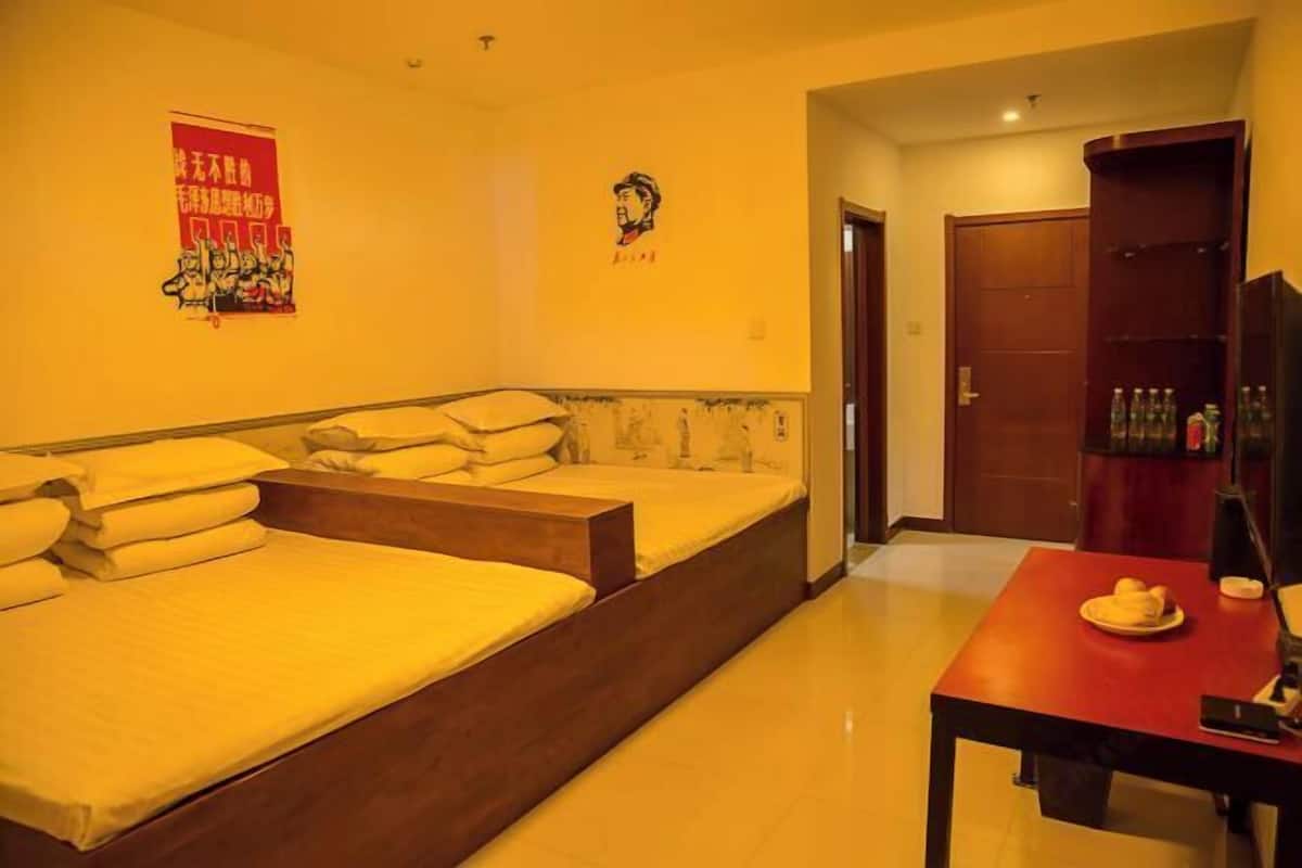 A hotel room with a large bed, a small table with a plate of food, and a wardrobe.