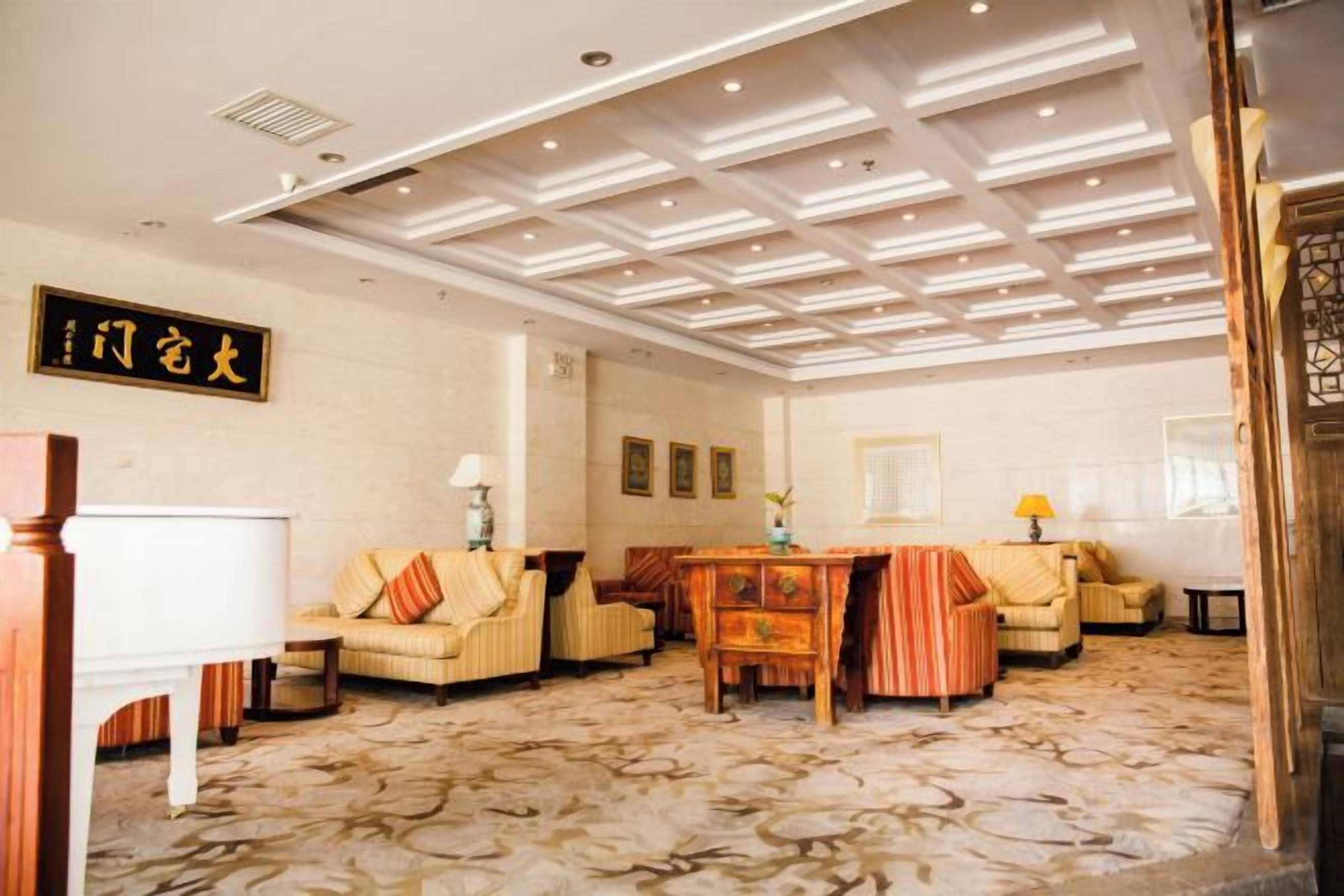 Una hall d'albergo con una moquette a motivi, un pianoforte, divani e un tavolo da pranzo.