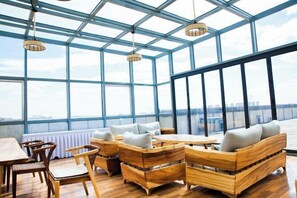 A spacious indoor area with wooden furniture and large windows offering a view of the cityscape. - Great Gate Hotel (Ordos)