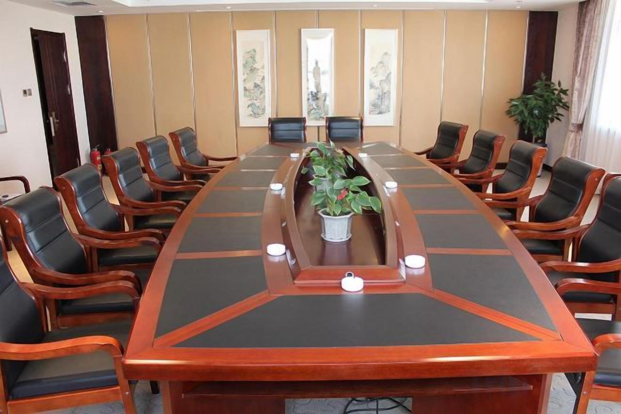 A conference room with a long table, chairs, and a plant.