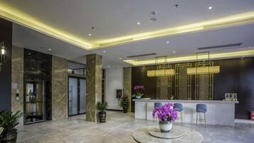 A modern lobby with a reception desk, seating area, and a marble floor.