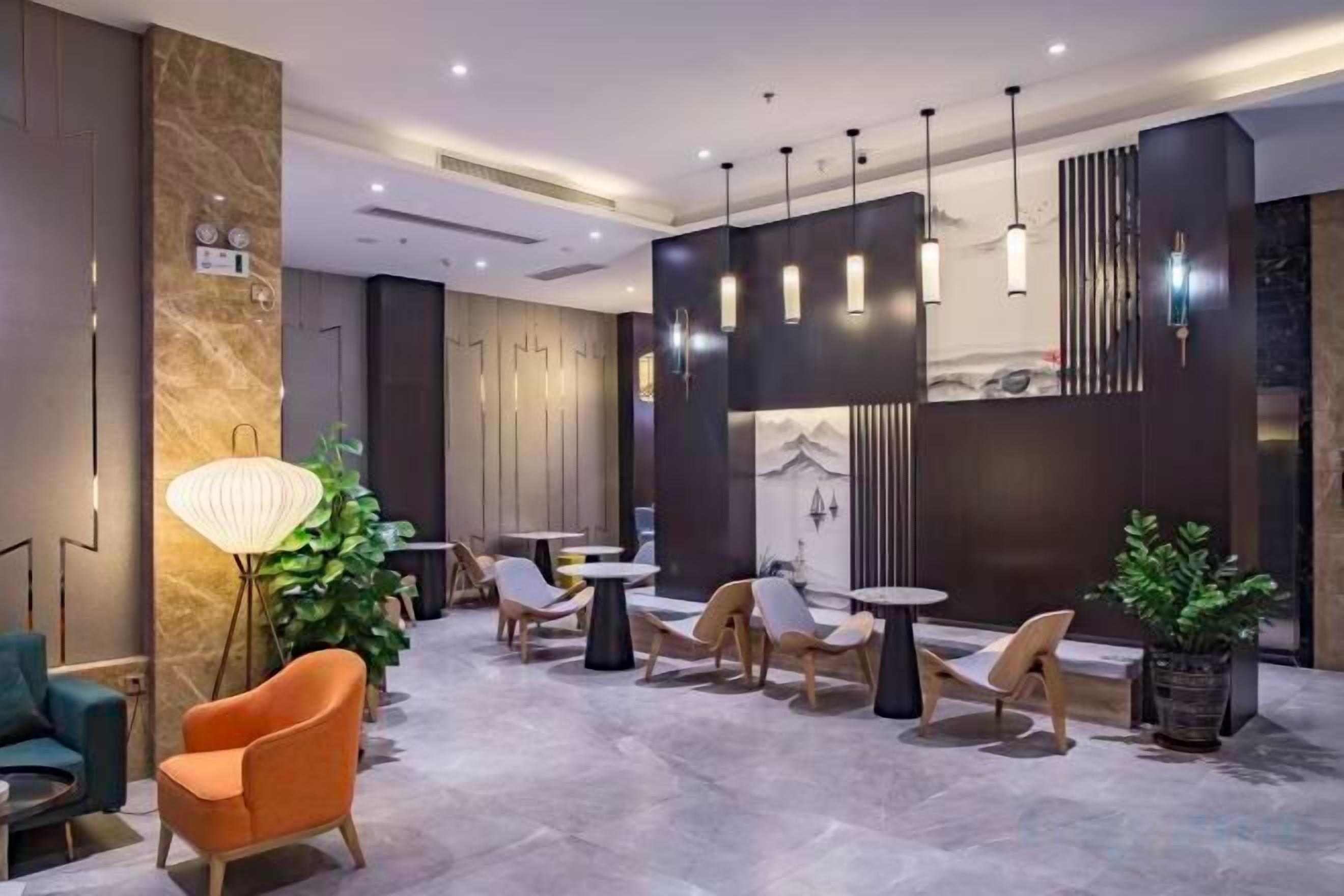 A modern lobby with seating arrangements, a large floor lamp, and pendant lighting.
