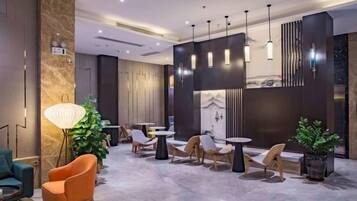 A modern lobby with seating arrangements, a large floor lamp, and pendant lighting.