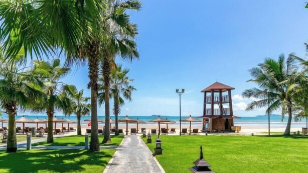 A pathway leading to a beachside area with palm trees, beach umbrellas, and a wooden structure. - Metropolis Hotel (Sanya Bay Coconut Dream Corridor) (Sanya)
