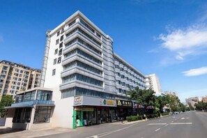 Et moderne hotel med flere etager, der har en markant indgang og en tydelig stueetage med butikker.