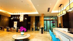 A modern lobby with a reception desk, seating area, and a large vase of flowers. - Metropolis Hotel (Sanya Bay Coconut Dream Corridor) (Sanya)
