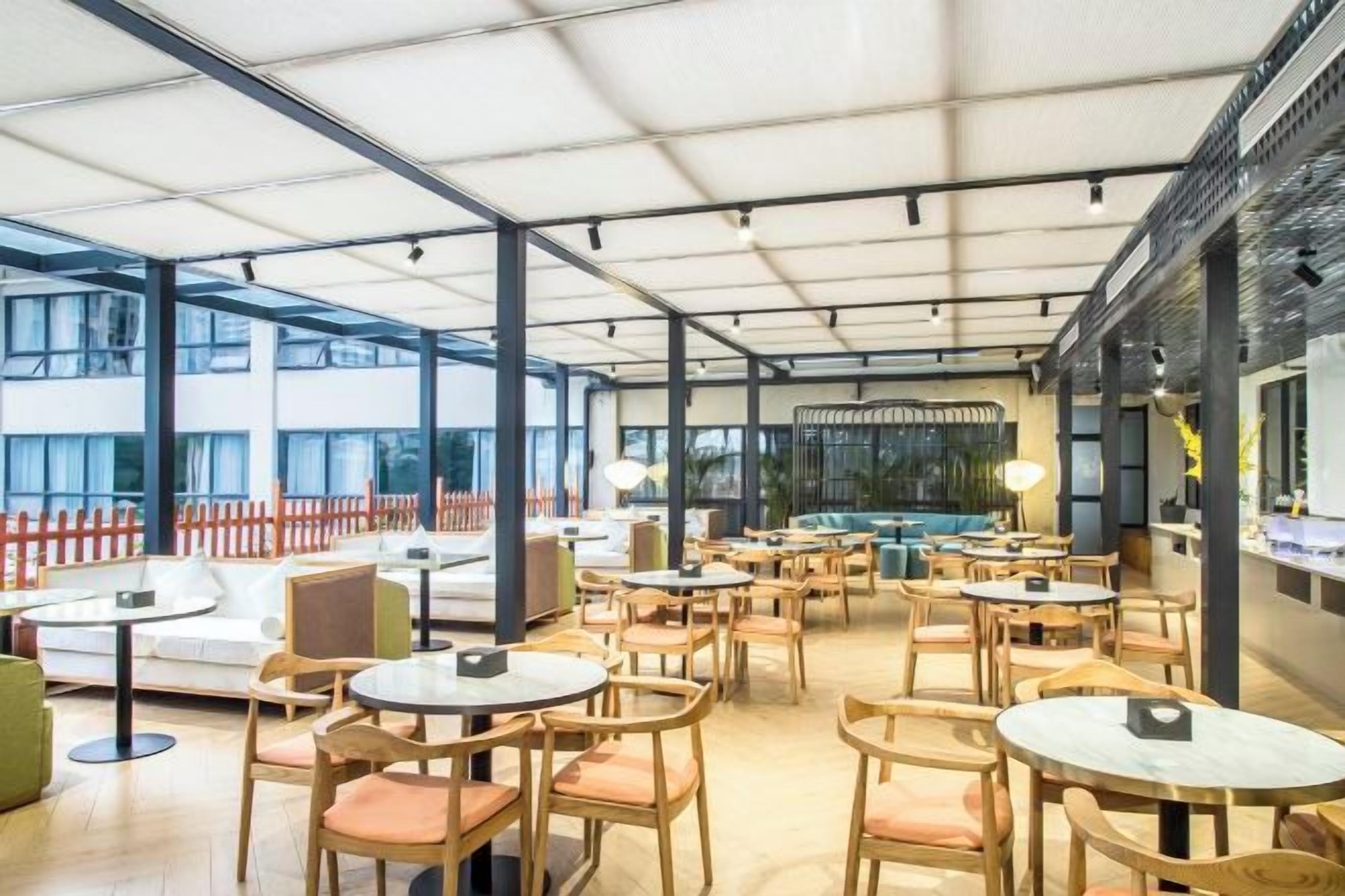 A spacious indoor seating area with round tables and chairs, large windows, and a modern interior design.