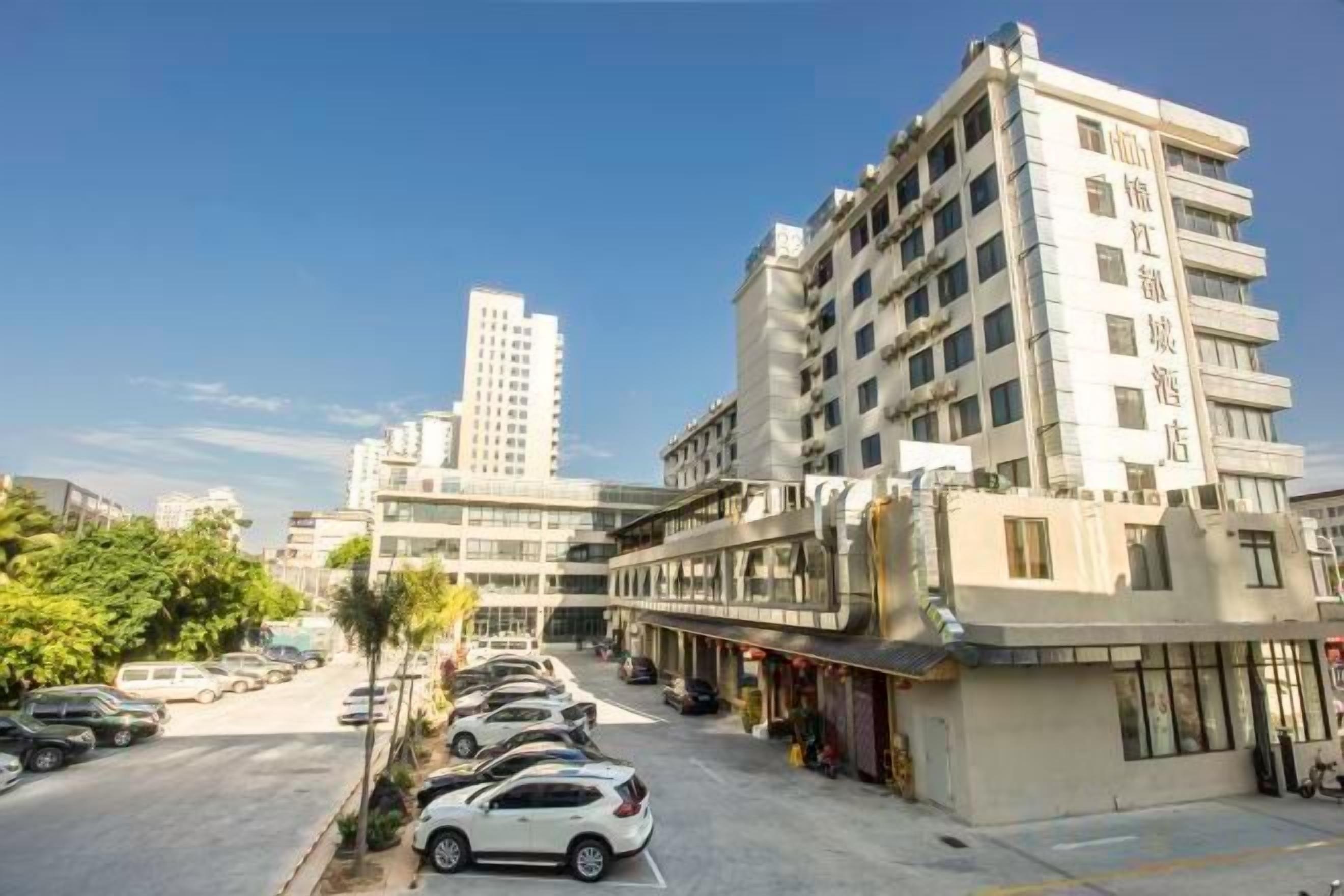 A multi-story hotel with a row of parked cars in front, a clear sky, and modern architecture.