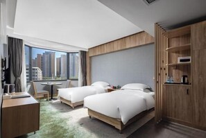 A hotel room with two beds, a desk, a chair, a small table, and a wardrobe.