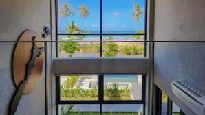A room with a large window overlooking a beach, a wooden sculpture, and a modern air conditioning unit. - The Hotel Elizabeth Resort and Villas (San Vicente)