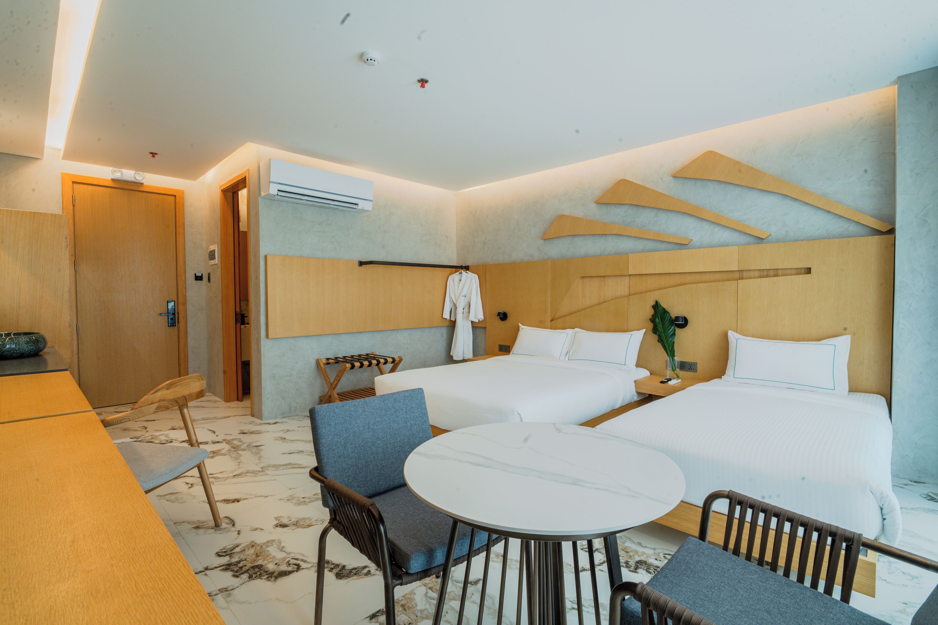 A hotel room with two beds, a round table, and a seating area with chairs.