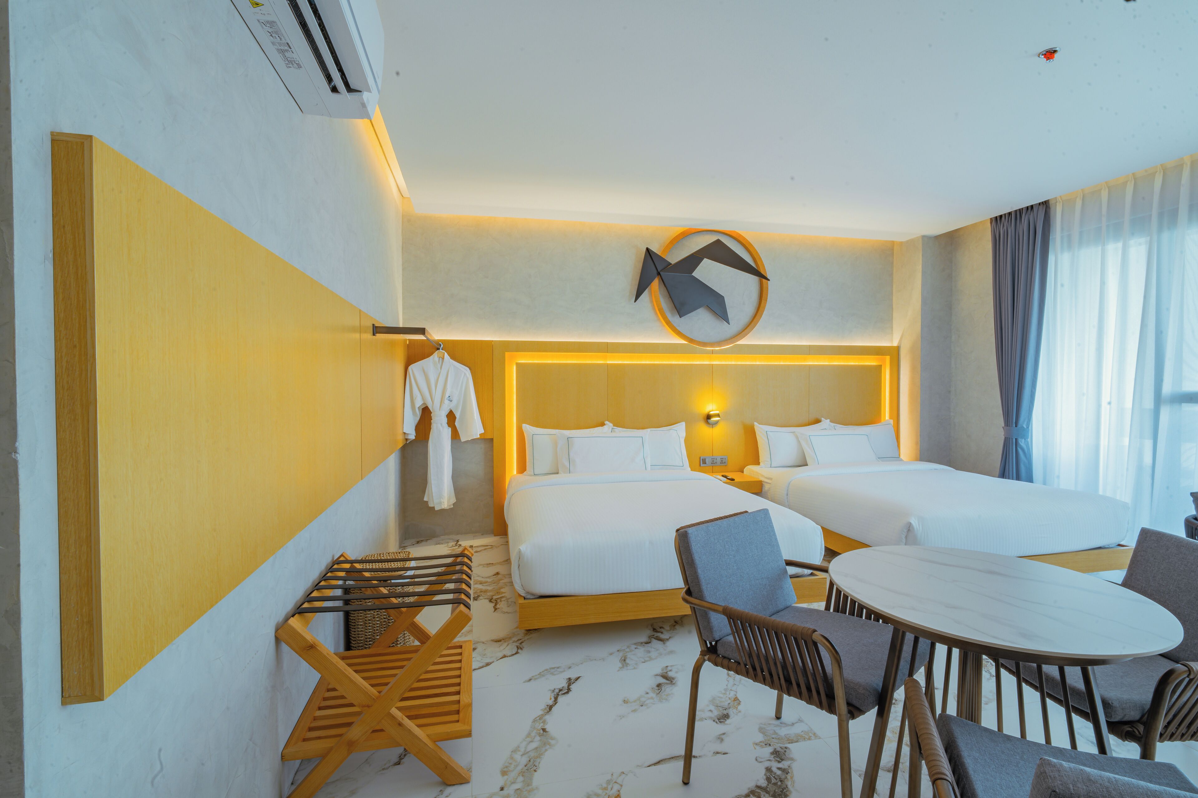 Ein Hotelzimmer mit zwei Betten, einem Esstisch und einer Sitzecke.