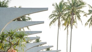 A modern building with curved architectural features, a pathway, and surrounding greenery including palm trees and plants. - The Hotel Elizabeth Resort and Villas (San Vicente)