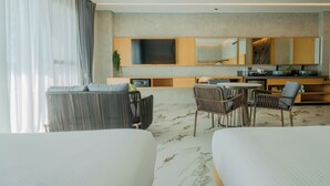 A modern hotel room with a large bed, a sofa, a dining table with chairs, a TV, and a kitchen area with a mirror. - The Hotel Elizabeth Resort and Villas (San Vicente)