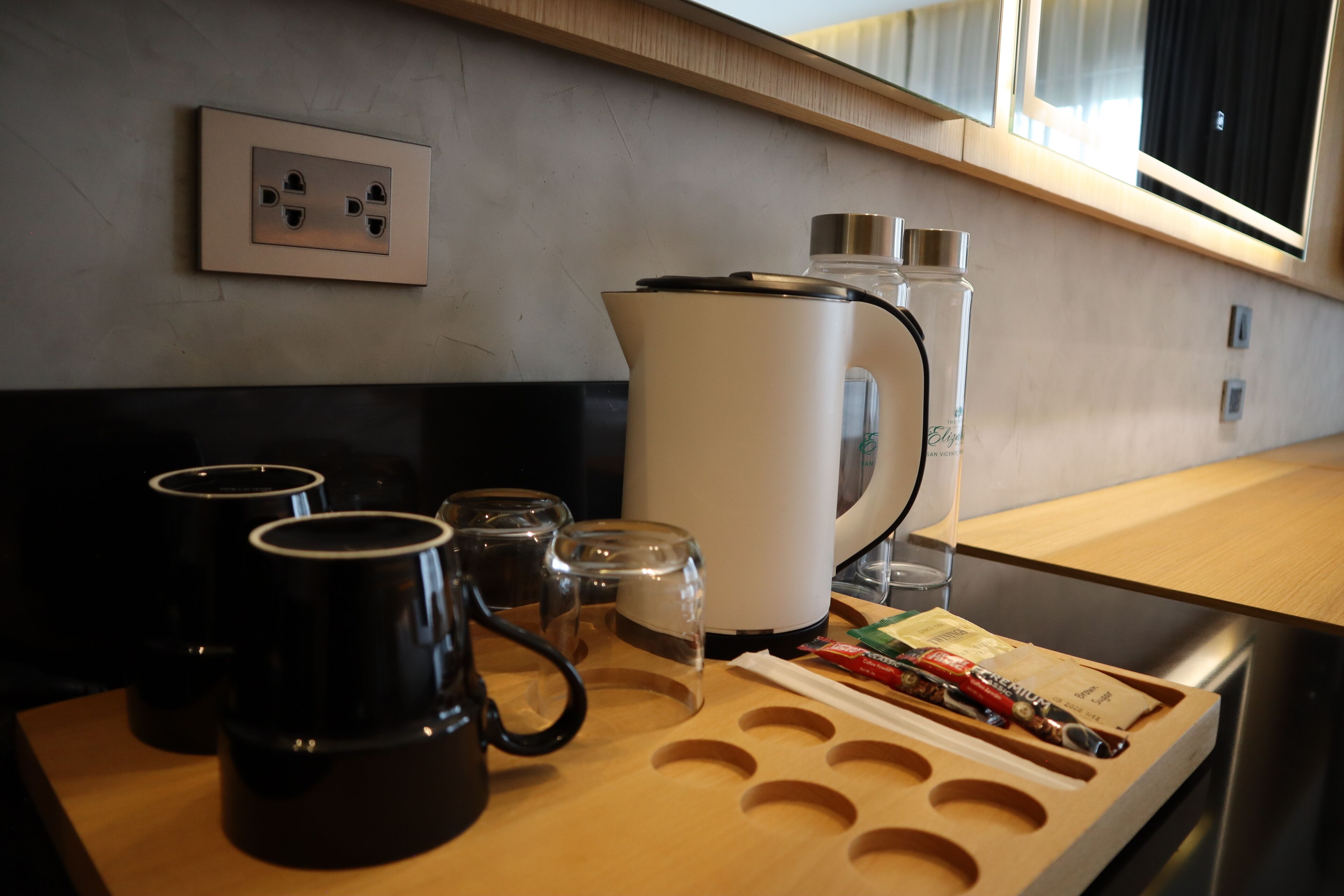 A kitchen counter with a coffee maker, mugs, and a kettle.