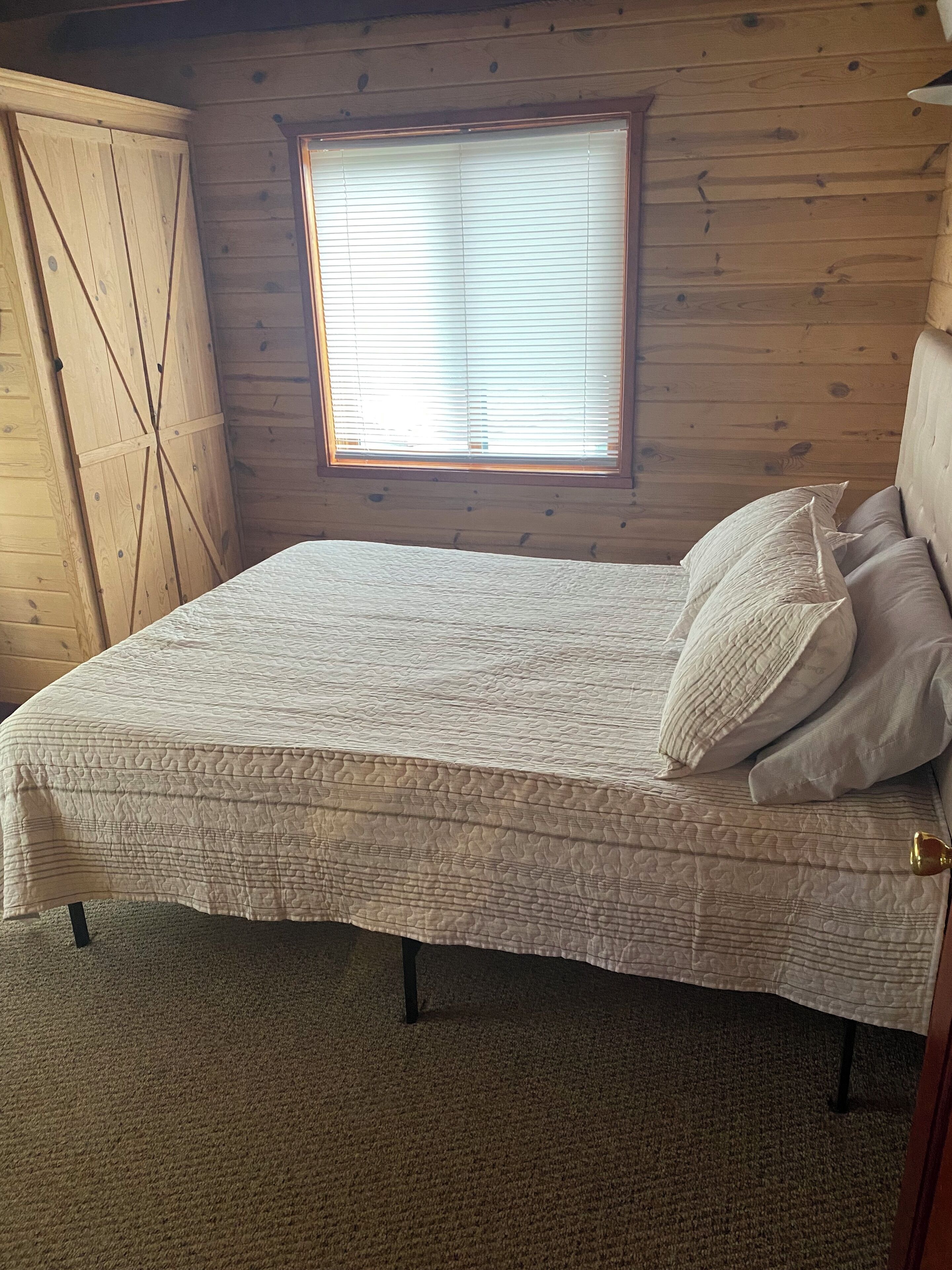 Ein Schlafzimmer mit einem Bett, einem Fenster und Holzwänden.