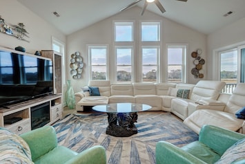 Living room with marsh view, vaulted ceiling, reclining leather couch & smart TV