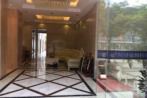 Una hall d'albergo con pavimento in marmo, un divano, un tavolino da caffè e una parete vetrata con vista.