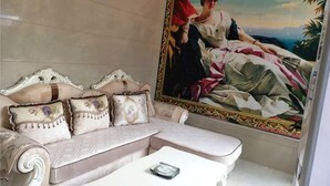 A room with a large painting, a cushioned sofa, and a small table.