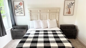 Ein Schlafzimmer mit einem großen Bett, zwei Nachttischen, einer Kommode und zwei an der Wand hängenden Bildern.