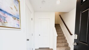 Ein Korridor mit Holzboden, einer weißen Tür und einer Treppe mit Handlauf.