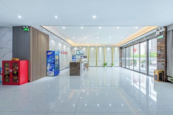 A modern hotel lobby with a reception desk, vending machines, and a glass partition wall. - Longding Business Hotel (Nanchang)