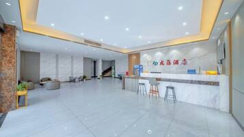 A spacious lobby with a reception desk, seating area, and a staircase leading to upper floors.