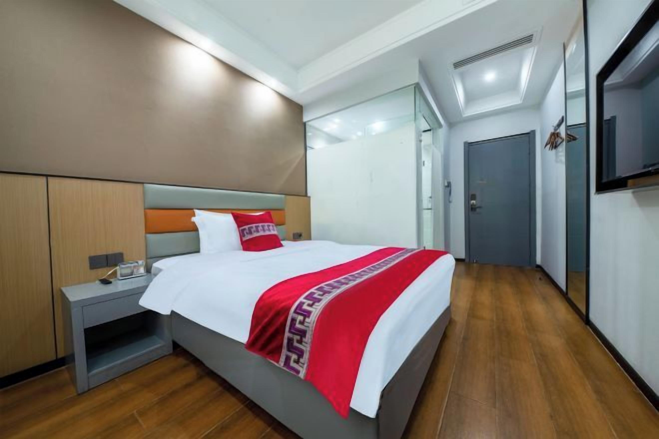 A hotel room with a bed, bedside table, and a TV on the wall.