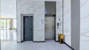 A modern elevator area with marble walls and a clean, tiled floor. - Longding Business Hotel (Nanchang)