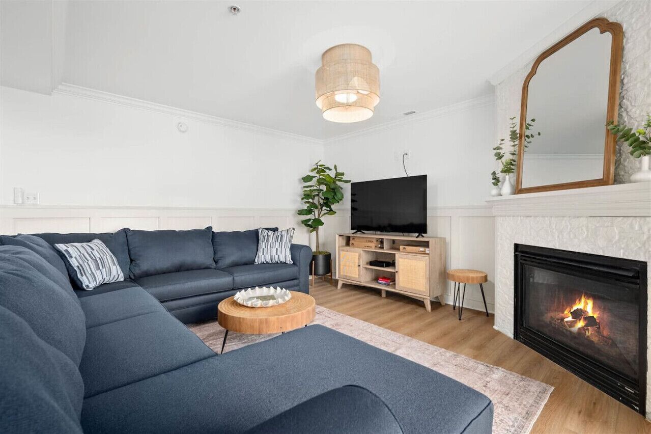 Una sala de estar moderna con un sofá seccional, un televisor, una chimenea y un espejo.