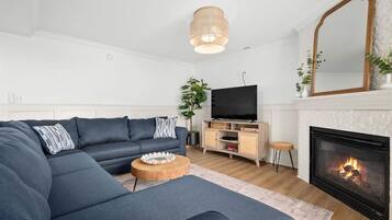 Una sala de estar moderna con un sofá seccional, un televisor, una chimenea y un espejo.