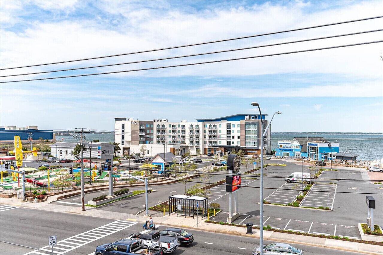 A coastal hotel with a modern design, a parking lot, and a view of the sea.