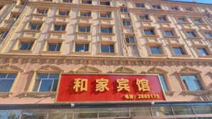 Un bâtiment avec une enseigne rouge sur laquelle on peut lire « 和家宾馆 » et un numéro de téléphone, le « 2885175 ».