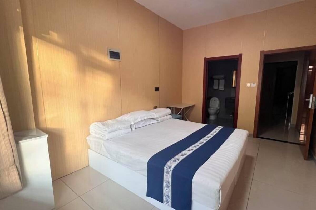 A hotel room with a large bed, a bedside table, and a wardrobe.