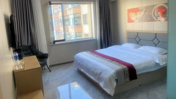 Hotelkamer met een groot bed, een raam met gordijnen, een stoel en een schilderij aan de muur.