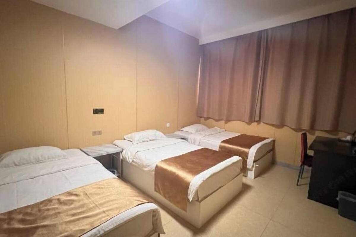 A hotel room with two beds, a desk, and a chair.