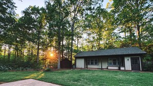 A single-story house with a dark roof and white walls, surrounded by a well-maintained lawn and tall trees. - Cozy North Raleigh Guest House - near RDU, DTR, + major Hospitals (Raleigh)