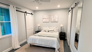 A bedroom with a bed, a ceiling fan, a window with curtains, a rug, and wall-mounted artwork. - Cozy North Raleigh Guest House - near RDU, DTR, + major Hospitals (Raleigh)