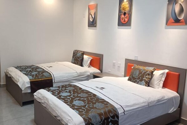 Two single beds with orange headboards, white bedding, and decorative pillows.