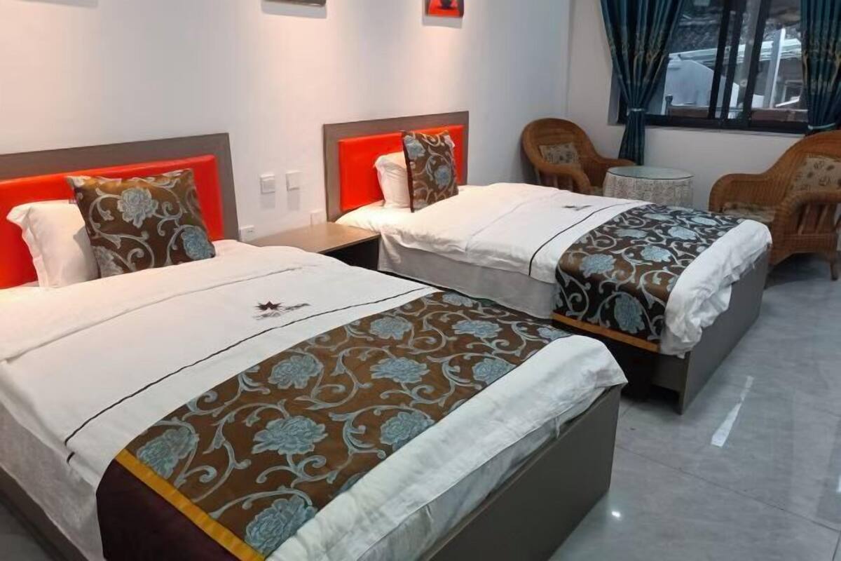 Une chambre d’hôtel avec deux lits, une petite table ronde et deux chaises.