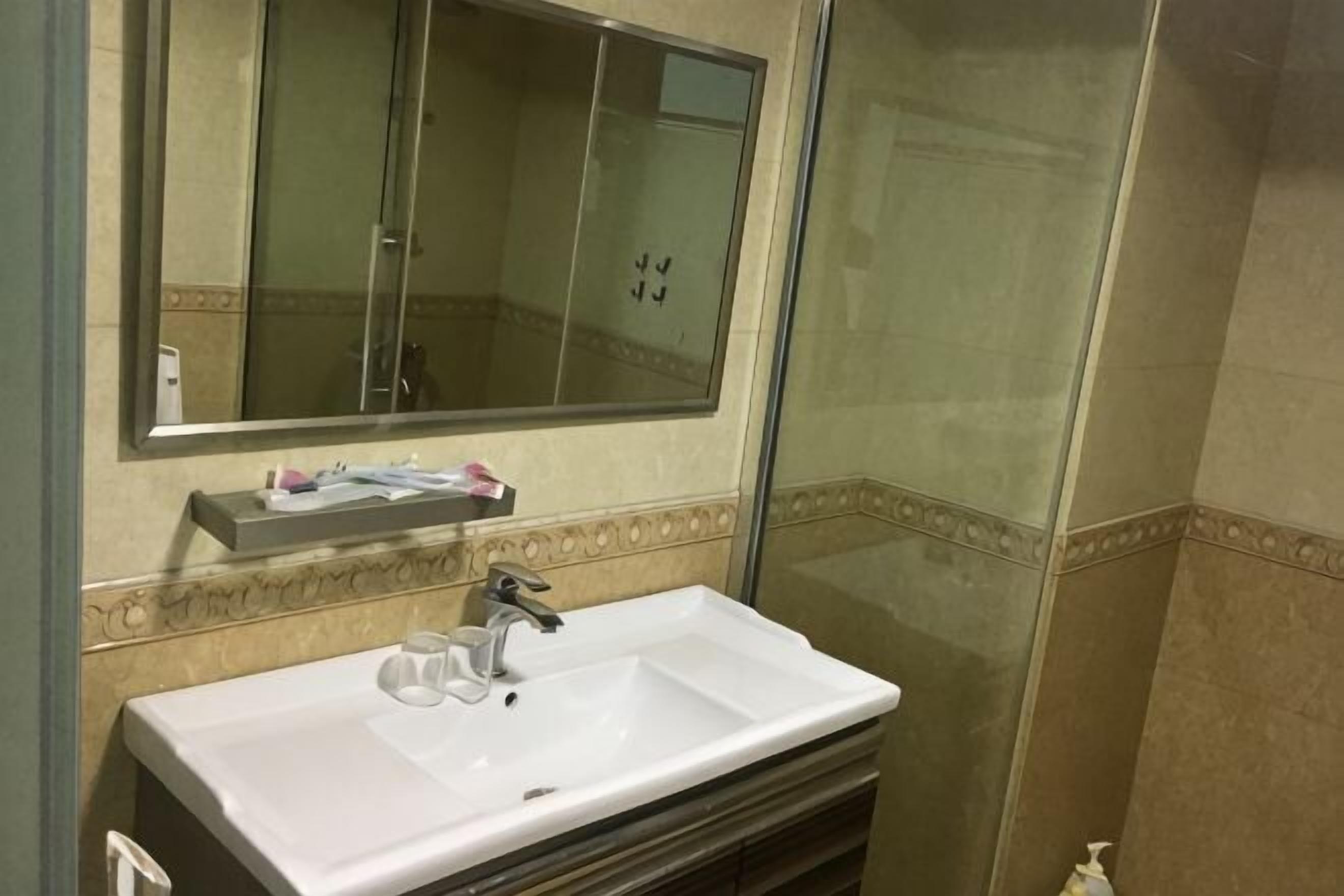 A bathroom with a white sink, a mirror, and a shower enclosure.