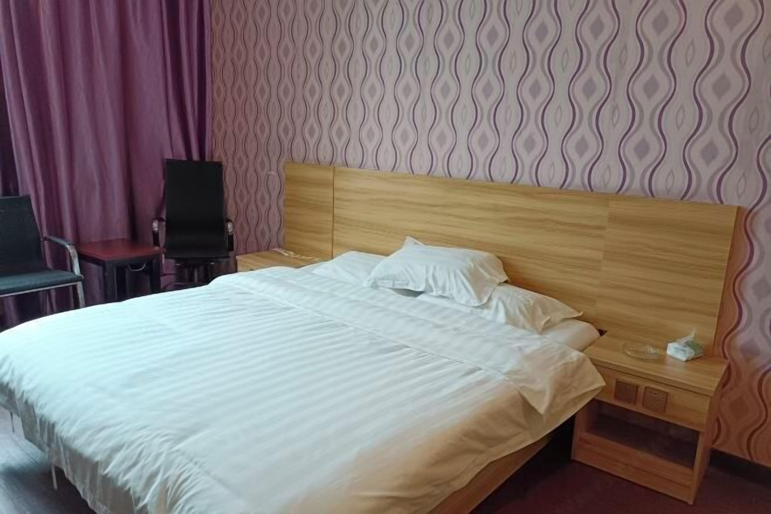 A neatly made bed with white linens in a hotel room.