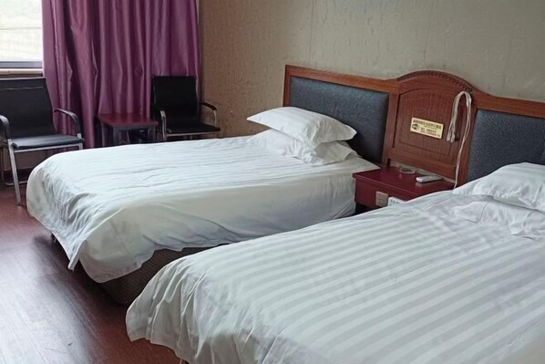 A hotel room with two single beds, a wooden headboard, a small bedside table, a chair, and a window with curtains. - Kangchao Hotel, Yueqing (Yueqing)